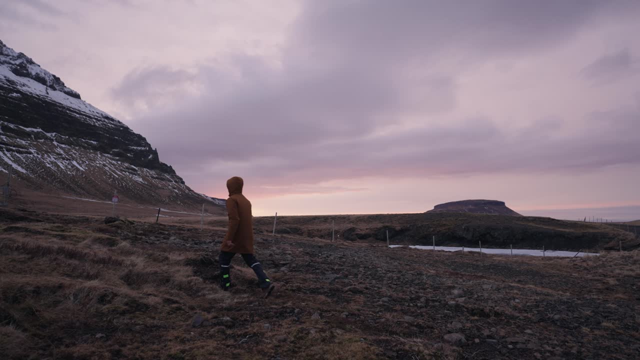 hombre caminando por el paisaje volcánico cerca de la montaña durante la hora dorada, islandia