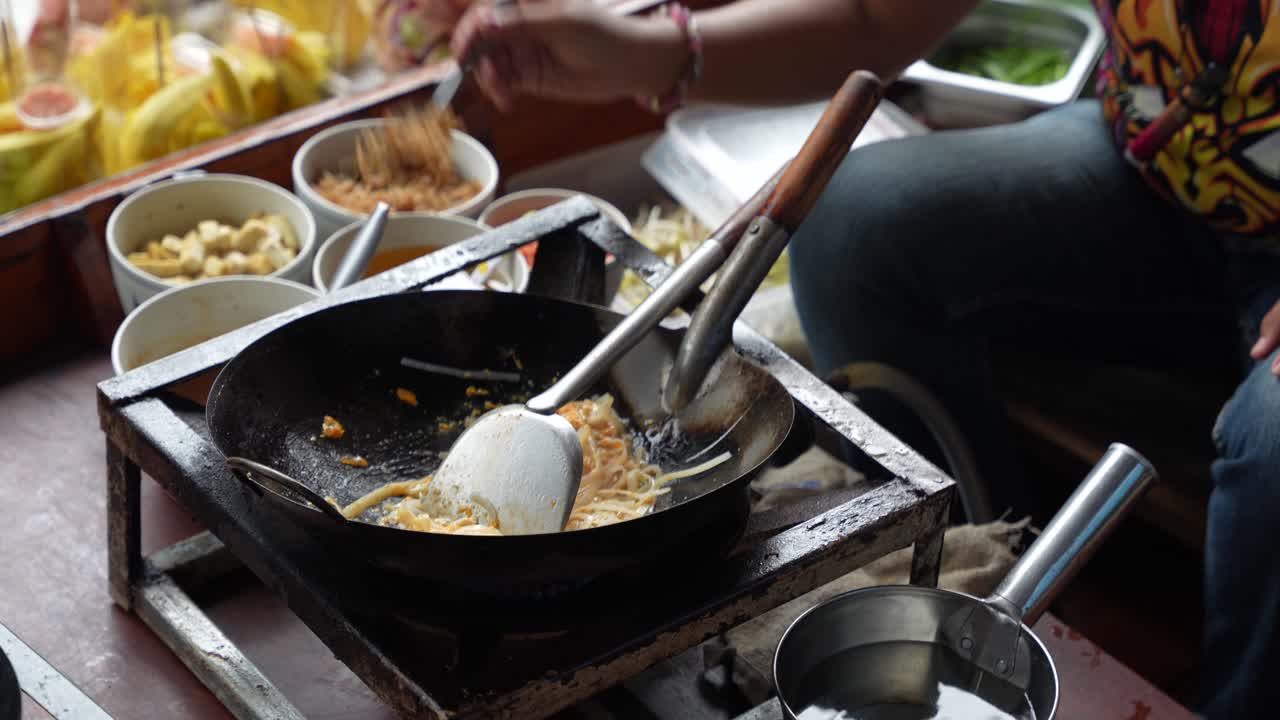 Street cooking in Thailand using a wok on a boat at a Damnoen Saduak Floating Market
