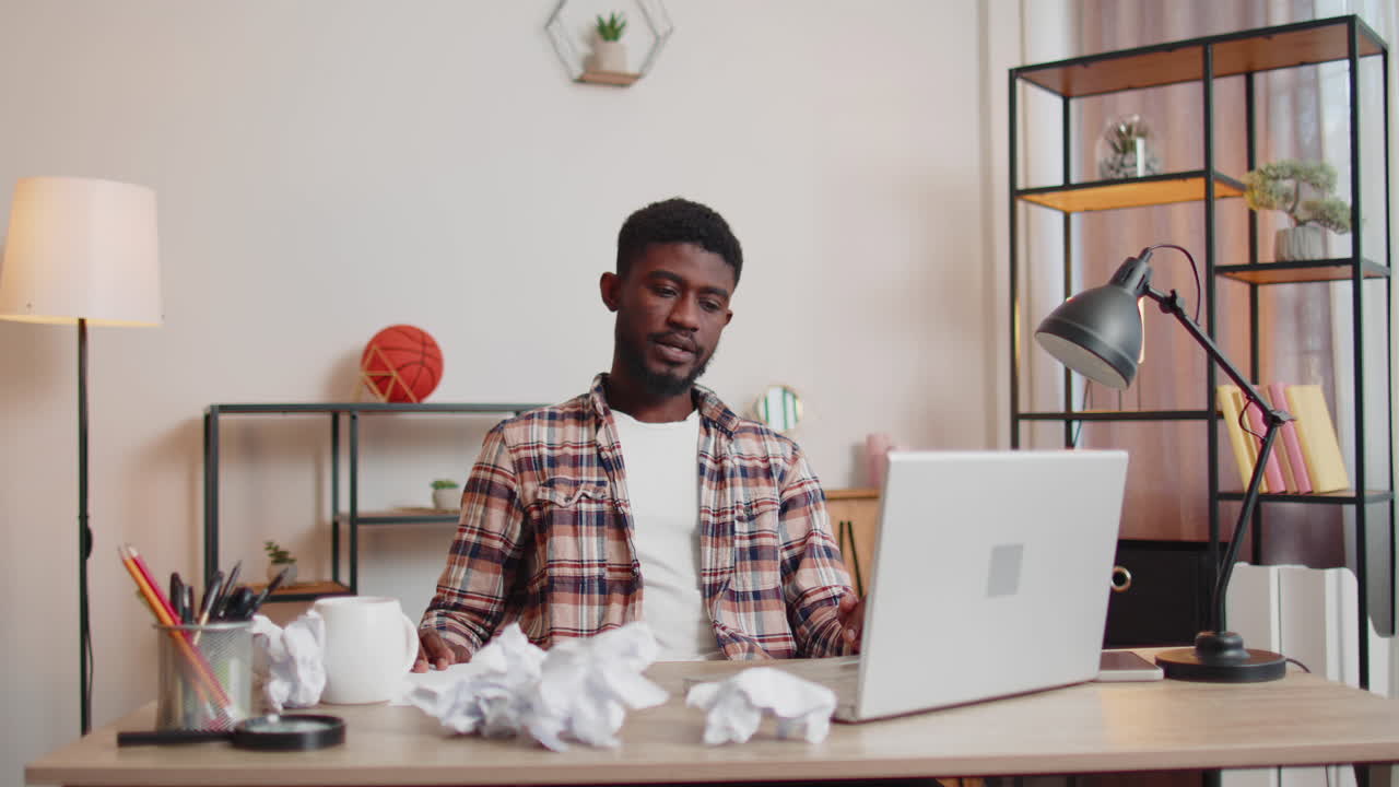 Angry furious man working at home office throwing crumpled paper, having nervous breakdown at work