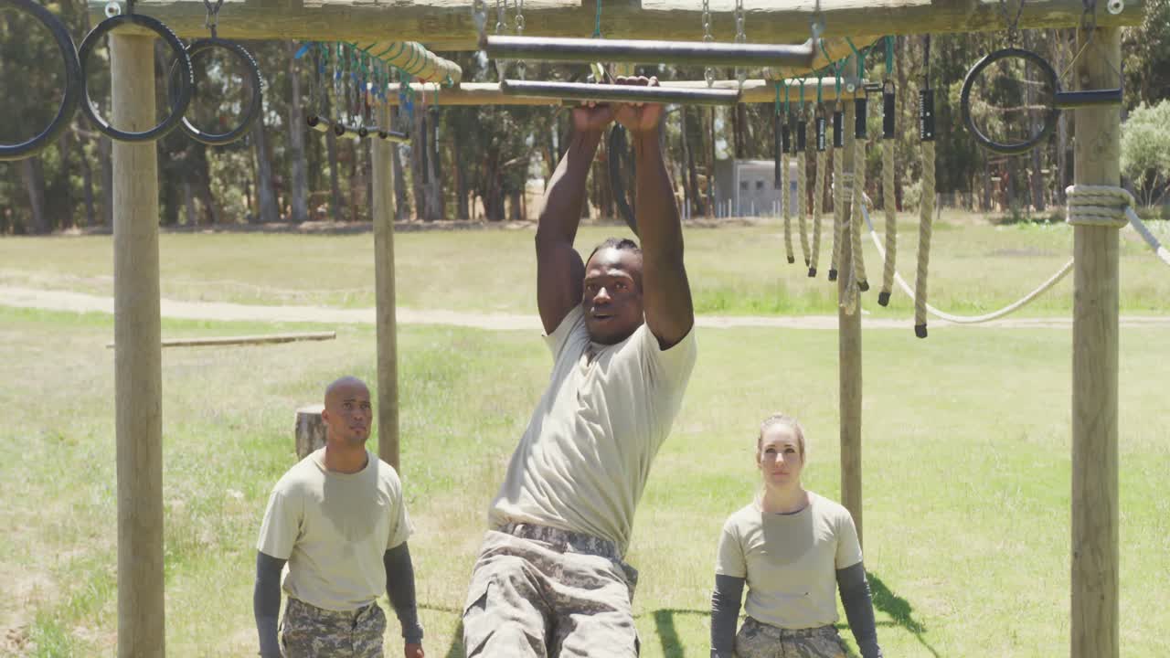 군대의 장애물 코스에서 트라페즈 바를 사용하는 적합한 아프리카계 미국 남성 군인