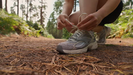 Close-Up-Of-Woman-Tying-Laces-On-Training-Shoe-Before-Exercising-Running-Along-Track-Through-Forest-Shot-In-Real-Time-1