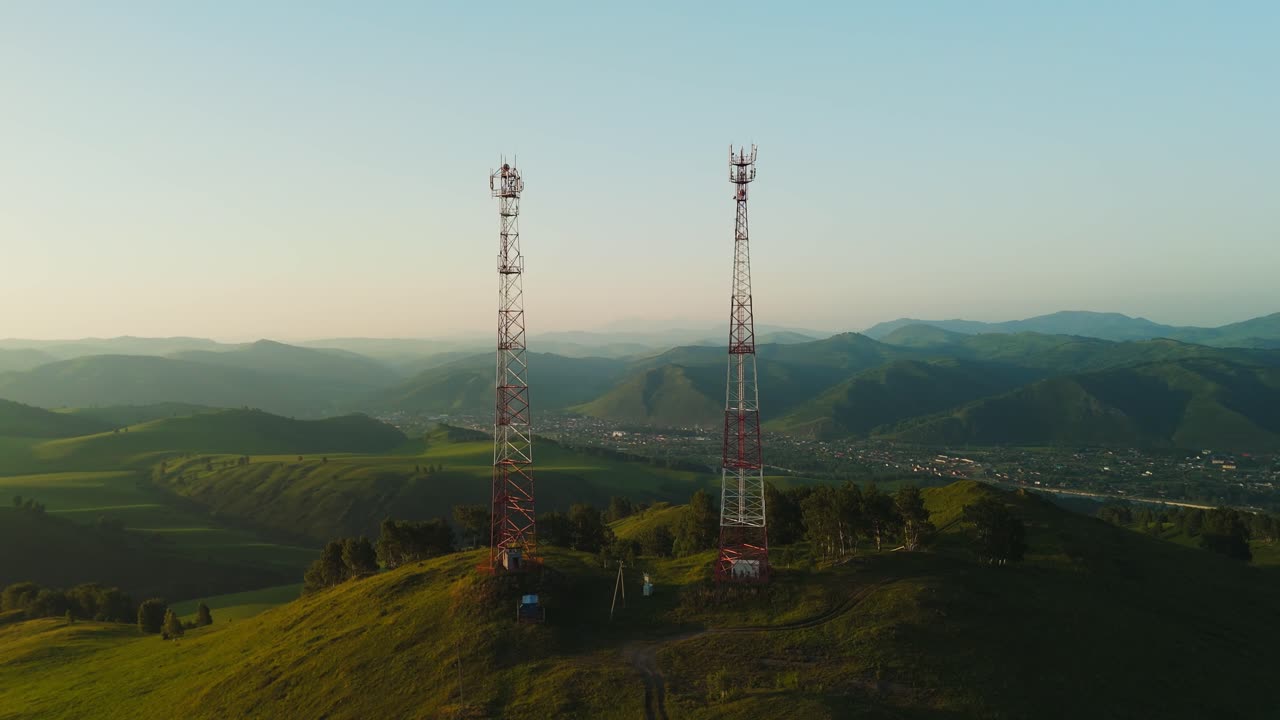 Torri di telecomunicazione su una collina verde con paesaggio montano