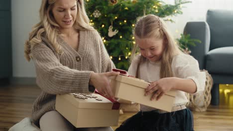 side view of caucasian girl and mother giving and receiving christmas gifts and later opening to check the content.