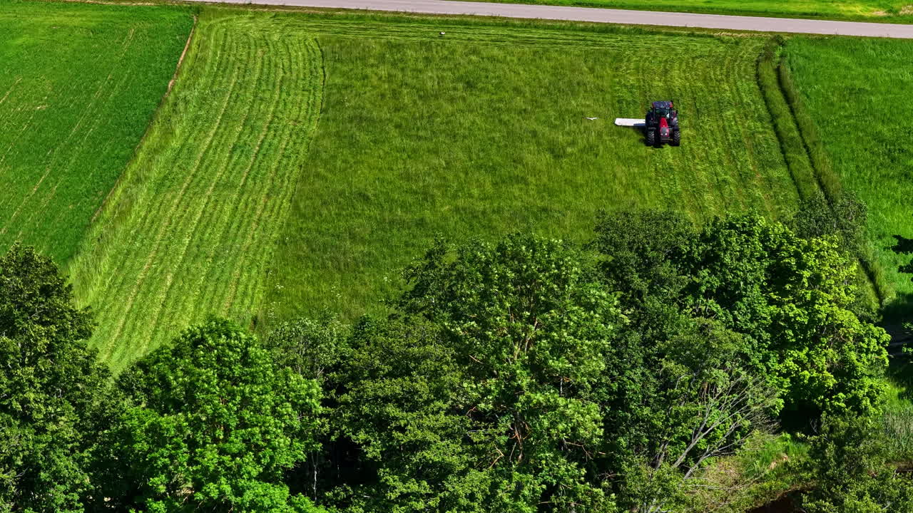 Tractor mowing a plot of land in slow motion. Aerial view