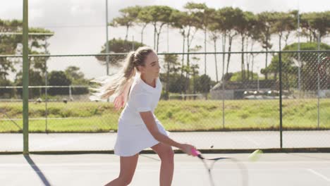 Video-of-midsection-of-caucasian-female-tennis-player-holding-racket-and-training-with-friend