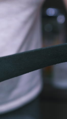 cu: person cleans black leather fabric strip holding in hands and standing in special workshop close view