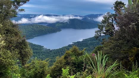 View-of-mountains,-clouds,-and-lush-green-forest-surrounding-Lake-Waikaremoana,-New-Zealand