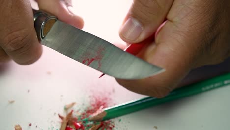 Footage-of-hands-slowly-sharpening-a-pencil-and-some-coloured-pencils-with-a-sharp-knife