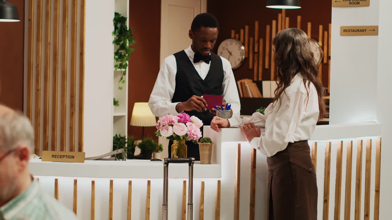 La réceptionniste de l'hôtel aide une femme.