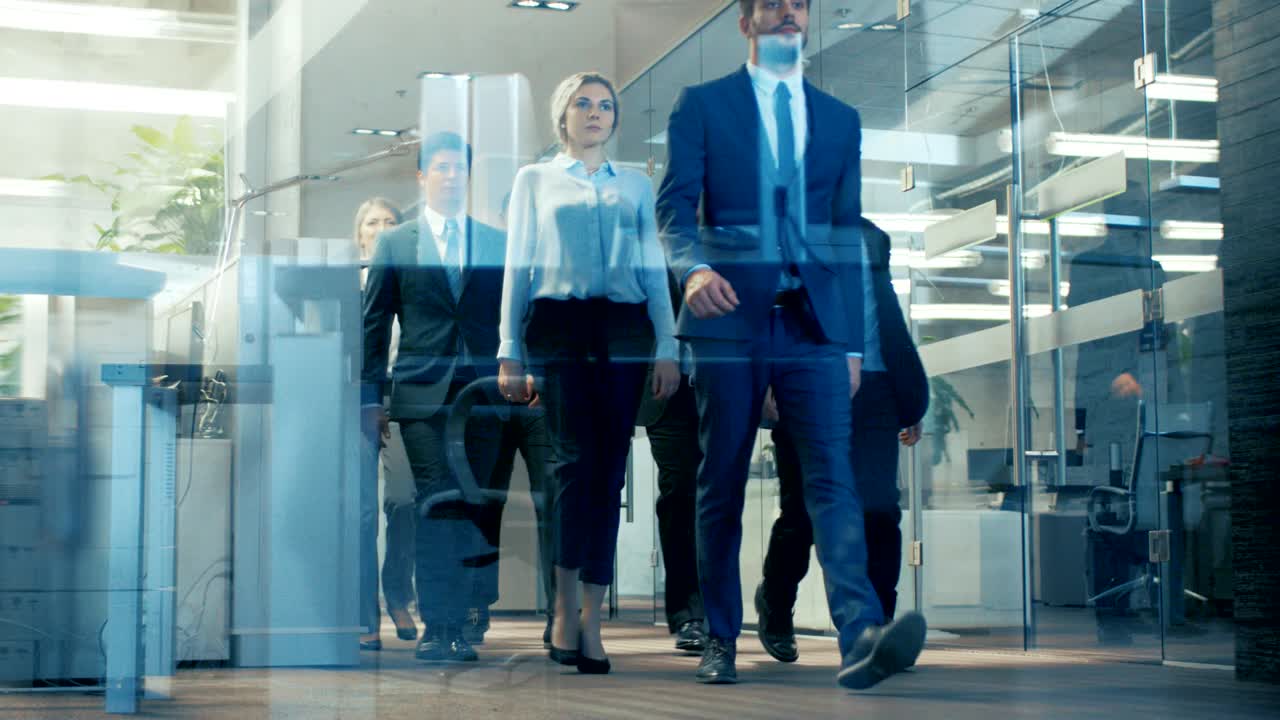 Low Angle Shot of the Delegation of Businesspeople/ Lawyers Confidently Marching Through the Corporate Building Hallway. Multicultural Crowd Of Businessmen and Businesswomen in Action.