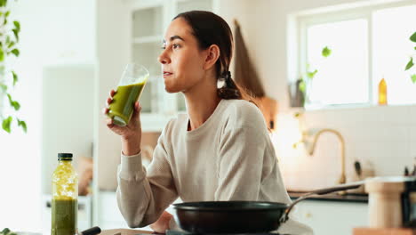 mujer disfrutando de un batido verde en su cocina