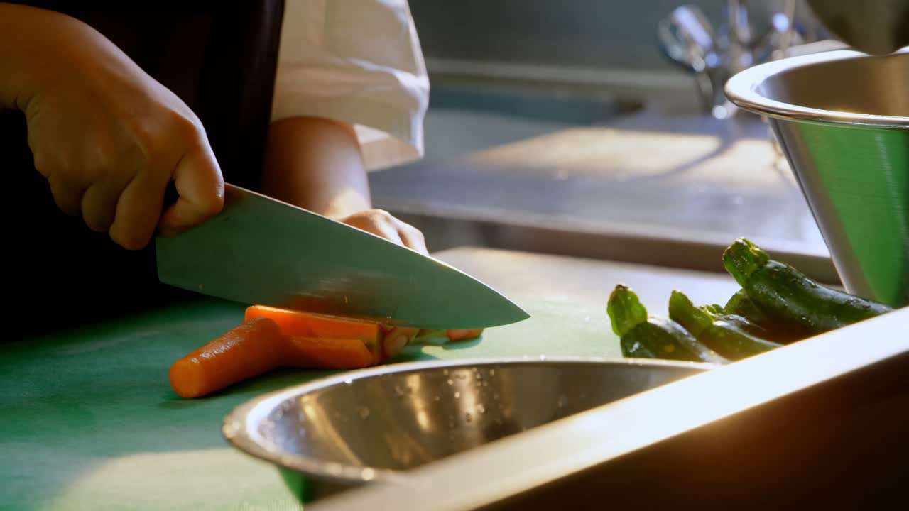 chef femenina cortando verduras en la cocina en el restaurante 4k