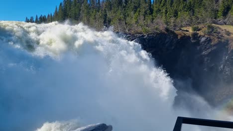 powerful shot of water thundering down sweden’s tallest waterfall, tännforsen, near åre. captured on a sunny day, the force and spray highlight the wild beauty of the nordic nature