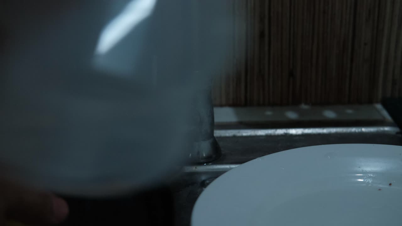 Hand turning pull-down faucet on at kitchen sink while washing dishes. closeup shot