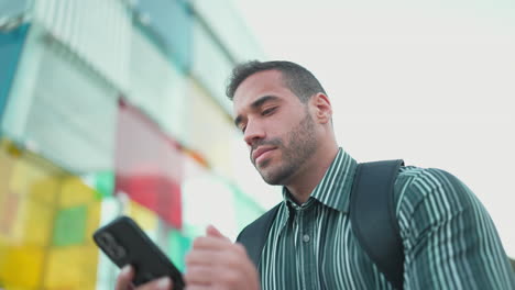 Young-man-checking-smartphone-while-standing-in-scooter-outdoors.