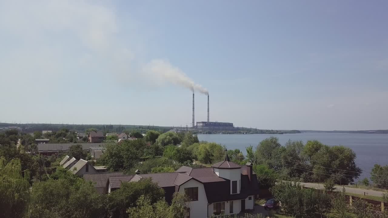 Beautiful view of the village and the river, surrounded by nature from the birds-eye view. Big power plant with pipes in the center of the village. Aerial view