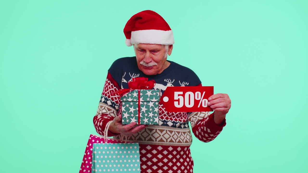 hombre anciano en suéter de navidad mostrando caja de regalos y 50 por ciento de descuento inscripciones texto de pancarta