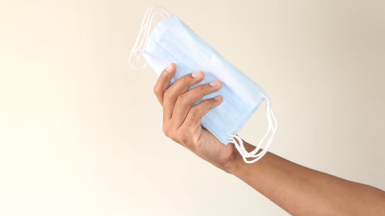 persona que sostiene una pila de máscaras faciales