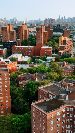 flying above the green residential area of new york with block of flat of unusual design. skyscrapers skyline at backdrop. vertical video