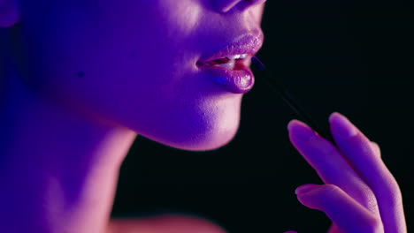 woman applying lipstick in neon lighting