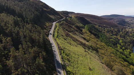 a car drives through the wicklow mountains overlooking lough tay, the guinness lakes