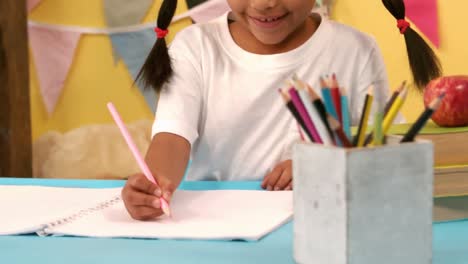 niña de escuela sonriente escribiendo en su bloc de notas