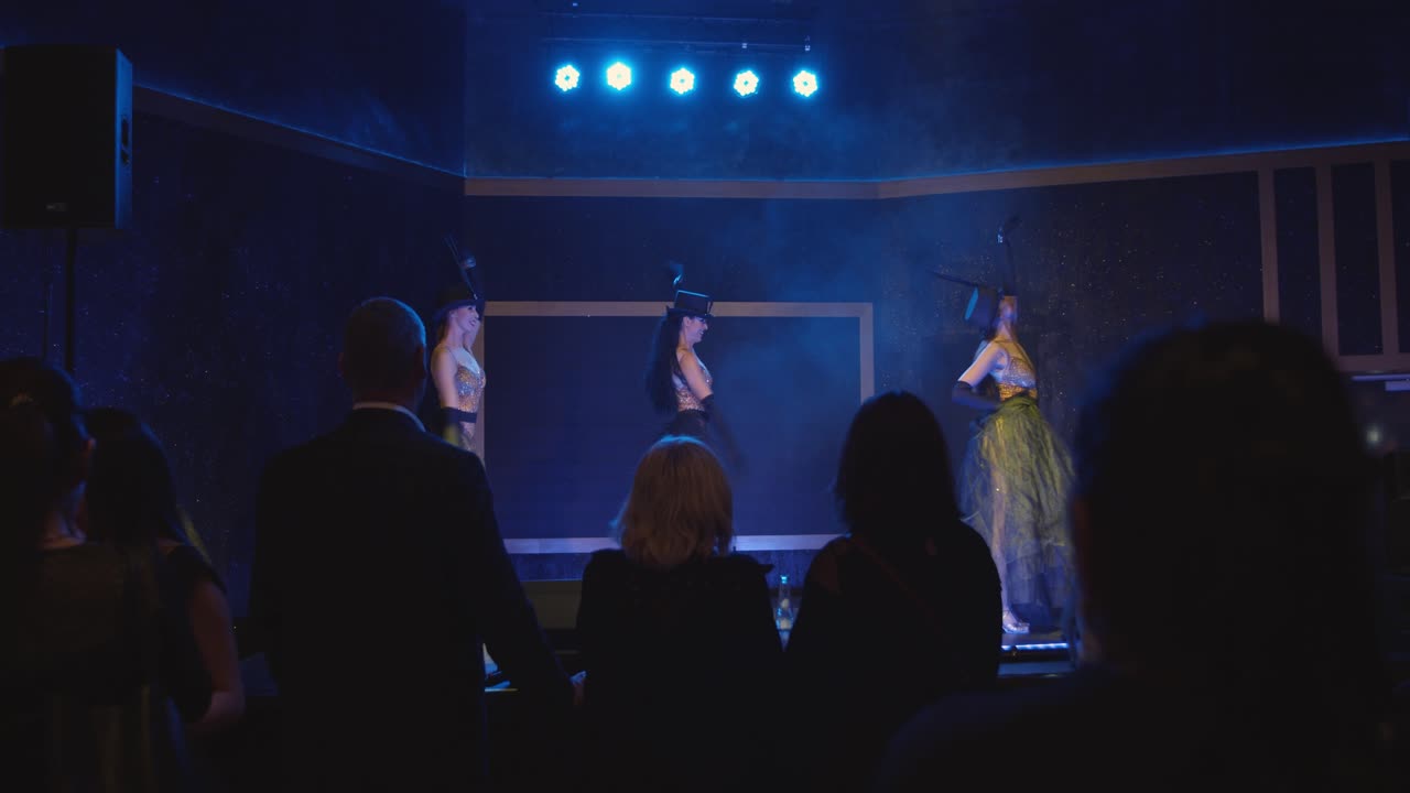 Group of fashionable ladies dancing on stage at night. Professional performance in concert hall.
