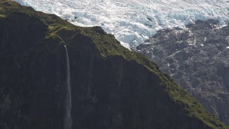 Long-waterfall-of-Bridal-Veil-Falls-falling-over-a-valley-with-glacial-ice-in-the-background