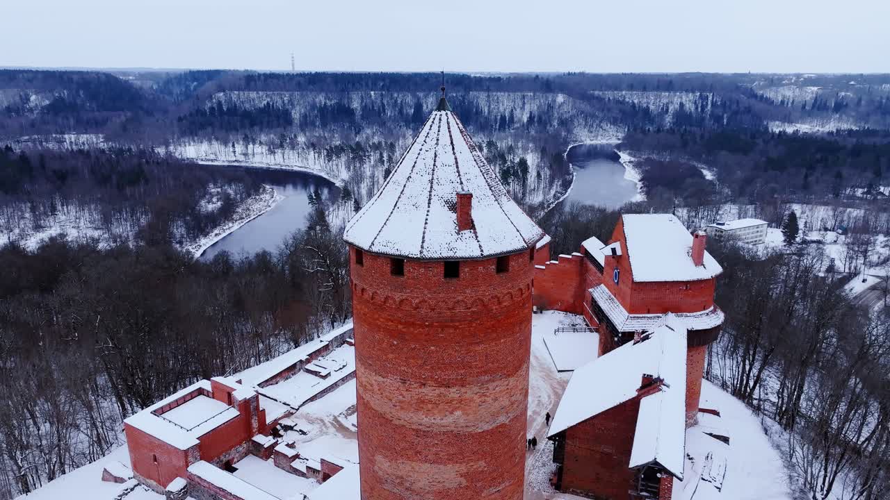 Snowy medieval fortress of Turaida overlooks Gauja River in Baltic landscape