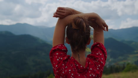 back view woman raising hands standing in front beautiful mountains close up.