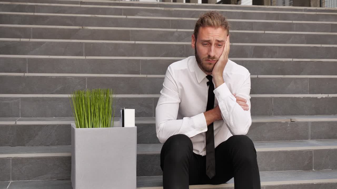 joven hombre de negocios en una camisa y corbata se sentó en los escalones buscando triste y preocupado