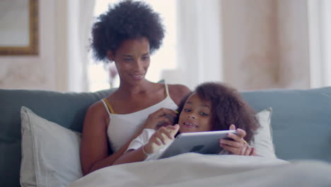 african american mother and daughter lying in bed and relaxing