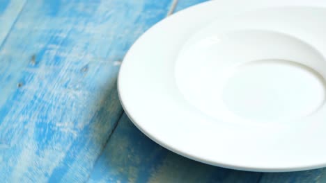 close up shot of a white plate rotating on a blue table.