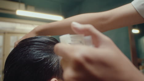 barber combing and spraying hair of client before haircut