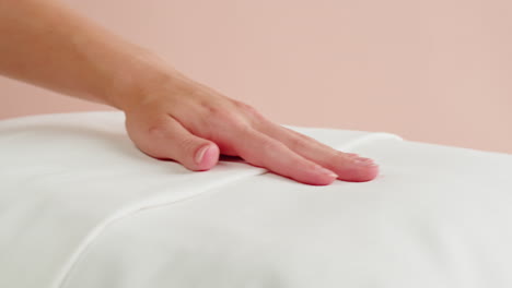 la mano de una mujer tocando una almohada blanca