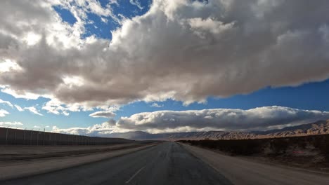 conduciendo a través del desierto de mojave directamente hacia las montañas distantes sin otros autos en el camino solitario - punto de vista del conductor