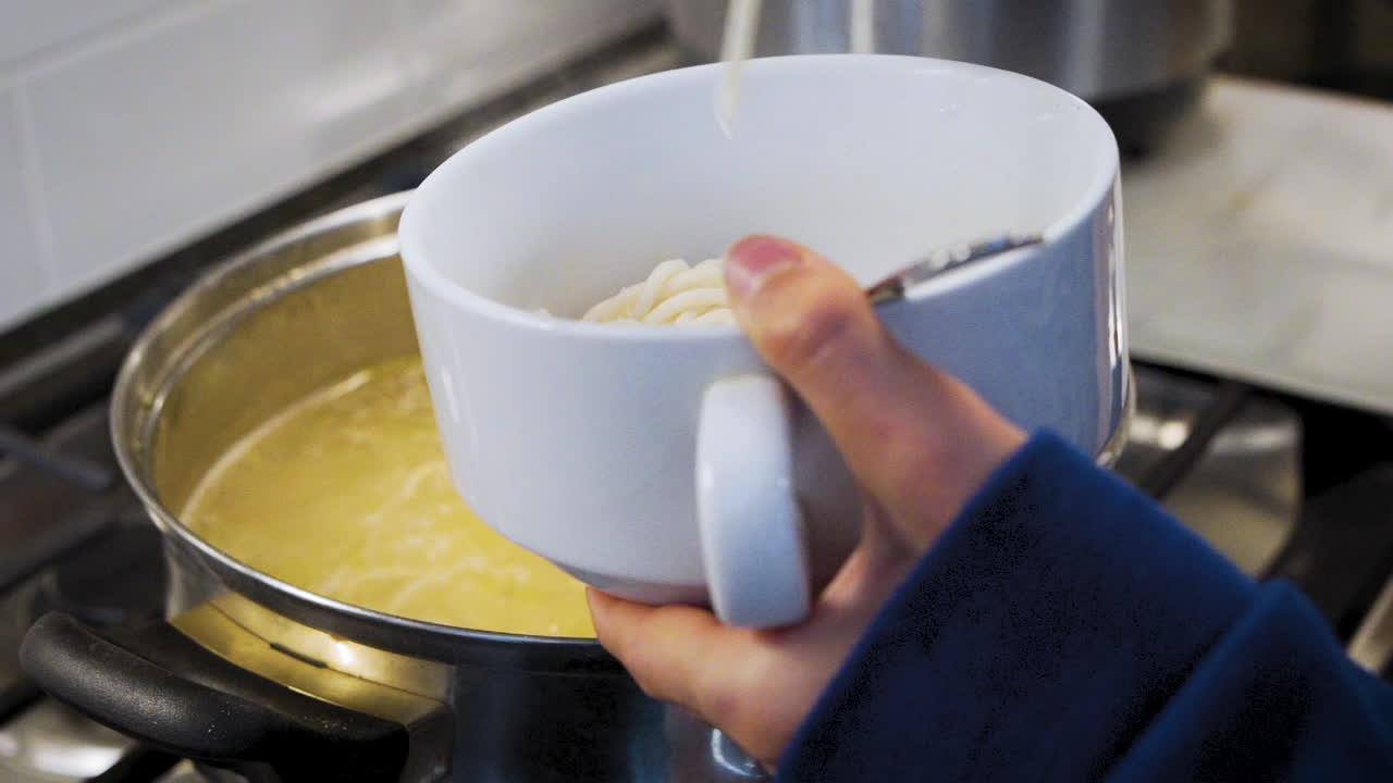 Mamma che riempie una ciotola di spaghetti in cucina