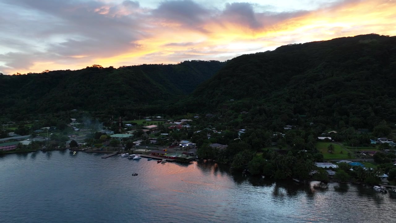 Alba drammatica sopra un villaggio di Tahiti, montagne e acqua, perfetta per temi di viaggio e turismo.