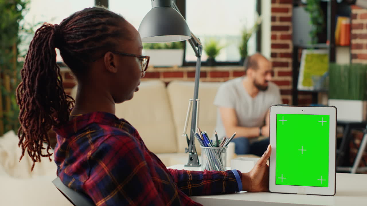 Female freelancer looking at digital tablet showing greenscreen