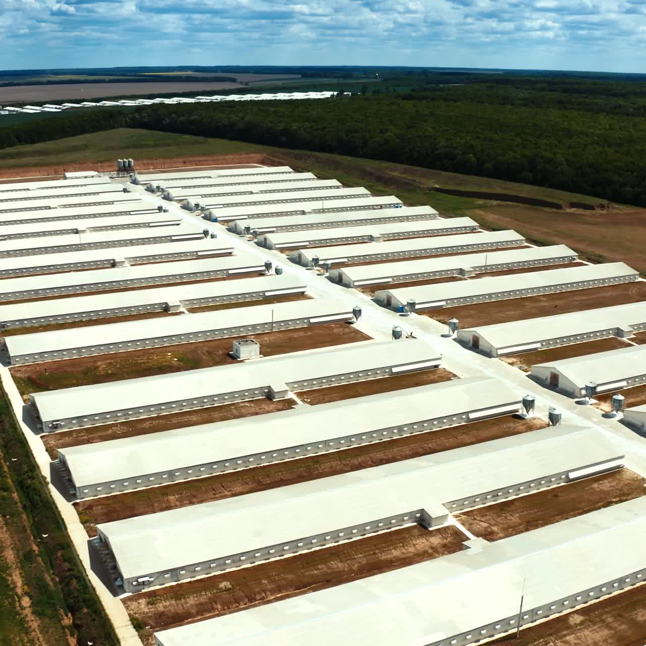 Modern manufacture complex on the field. Panoramic view of industrial plant. Flight over the farm on nature background. Aerial view.