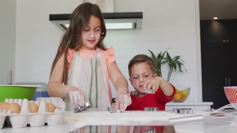 hermanos caucásicos felices horneando juntos, preparando galletas en la cocina