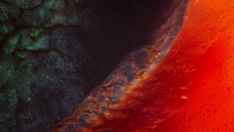 macro view of green and orange-pink inks flowing and collapsing into each other, forming a black shimmering pigment