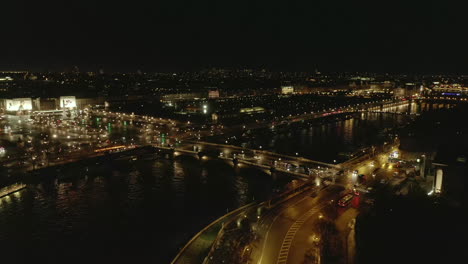 Imágenes-Aéreas-De-La-Ciudad-De-Noche.-Vehículos-Que-Circulan-Por-El-Pont-De-La-Concorde-Y-Los-Paseos-Marítimos-Del-Río-Sena.-Plaza-Pavimentada-Place-De-La-Concorde-Con-Obelisco-De-Luxor-En-El-Medio.-París,-Francia