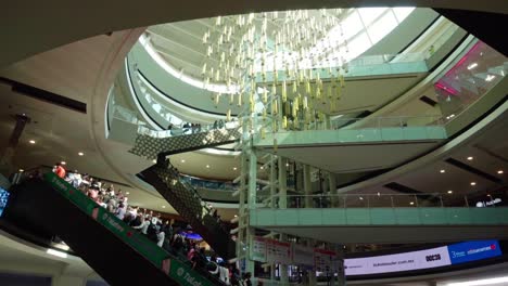 shoppers move through a modern mall with artistic lighting and high ceilings in a busy atmosphere
