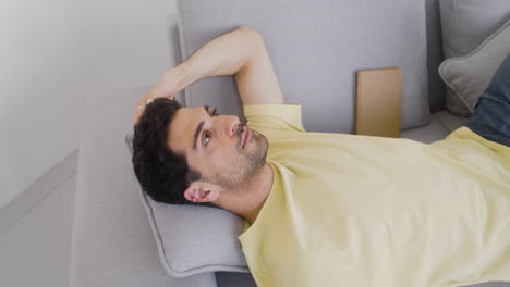 a dark haired man dozes on a sofa