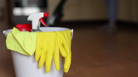 4k video footage detergents in a bucket on the floor and woman cleaning her home in the background