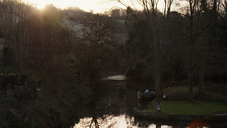 tranquil pond in a park at sunset in bath, england - wide shot