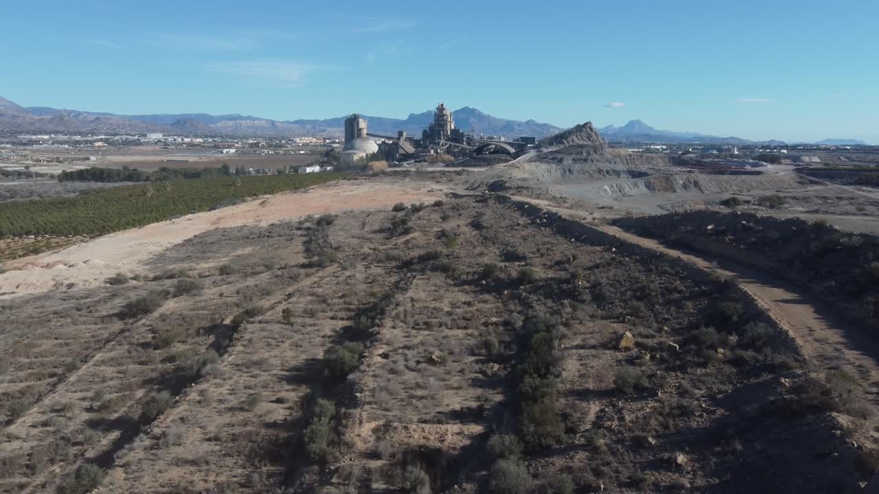 Aerial revealing a large cement factory. Dust in the air.