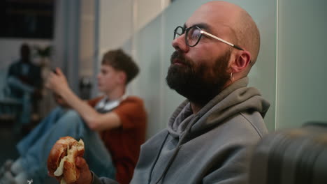 friends relaxing and eating burgers in a modern office