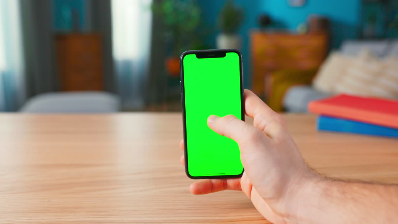 Close-up of a Man Holding and Making Hand Gestures on a Modern Green Mock-up Screen Smartphone. Touching Mobile Phone Chroma Key Screen with a Finger